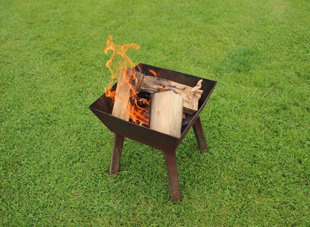 Metal Fire Pit with Wooden Logs on Grass